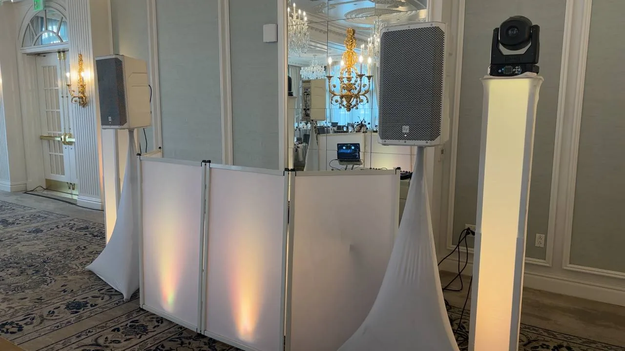 Close-up of the elegant white DJ facade with colorful gobo lighting wash and twin speakers at Hotel Carmichael